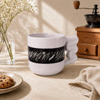 Abstract black brushstroke band on a light porcelain coffee mug