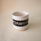 Zigzag sculptural handle on a black and white ceramic mug