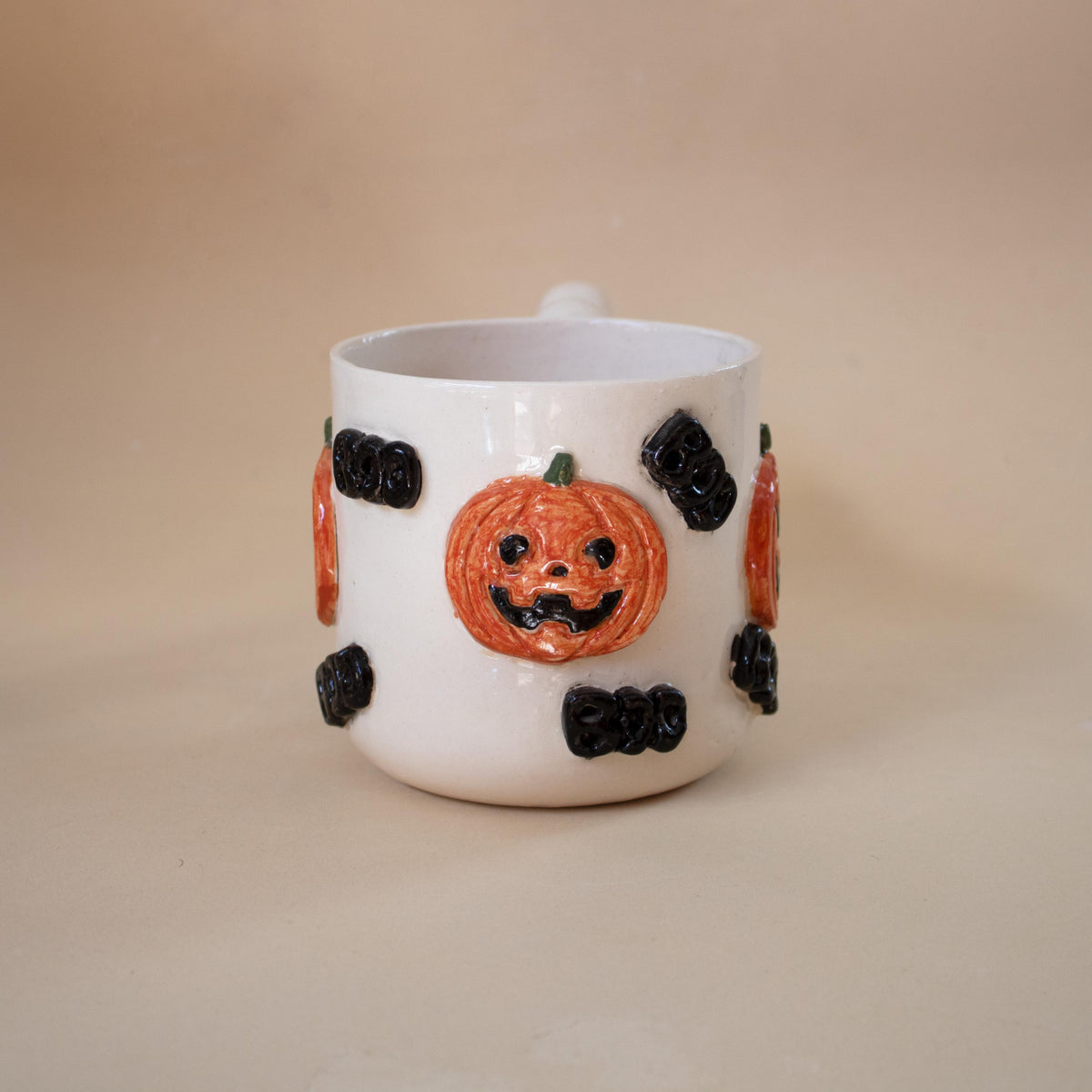 Raised boo letters on a handmade pumpkin coffee mug
