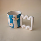 Fried egg motifs over vibrant blue stripes on a coffee mug