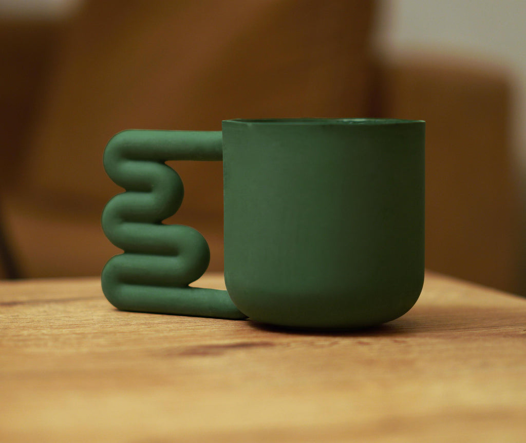 Dark green handmade mug styled with natural textures