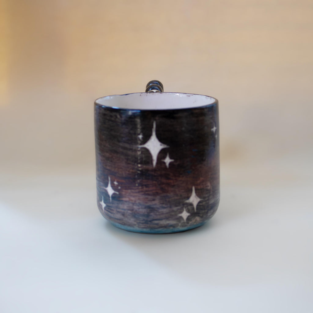 Wavy sculptural handle on a galaxy ceramic cup