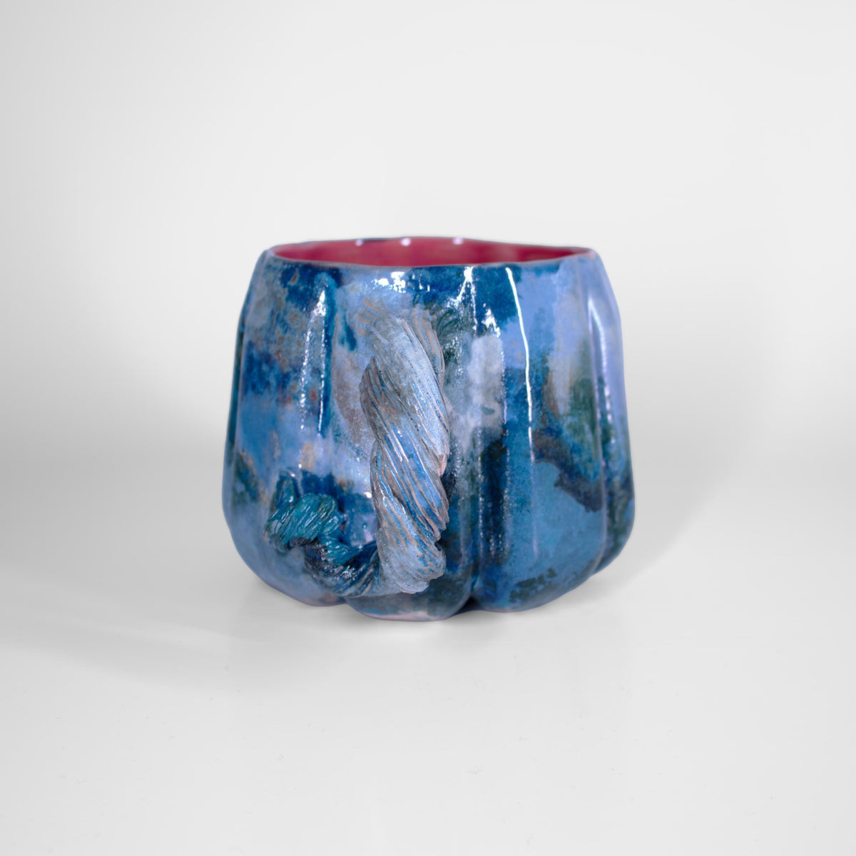 Berry-pink glazed interior of a blue pumpkin mug