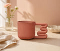 Terracotta coral porcelain mug with squiggle handle by HUE Atelier