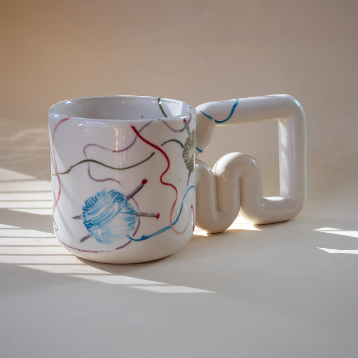 Colourful yarn balls painted on a white coffee mug